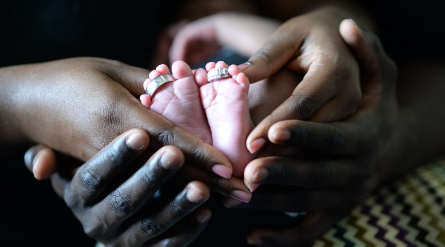 person touching baby's feet with two silver-colored rings