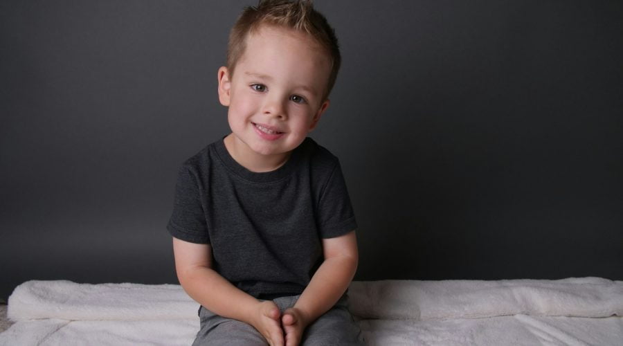 boy in black crew neck t-shirt sitting on white bed