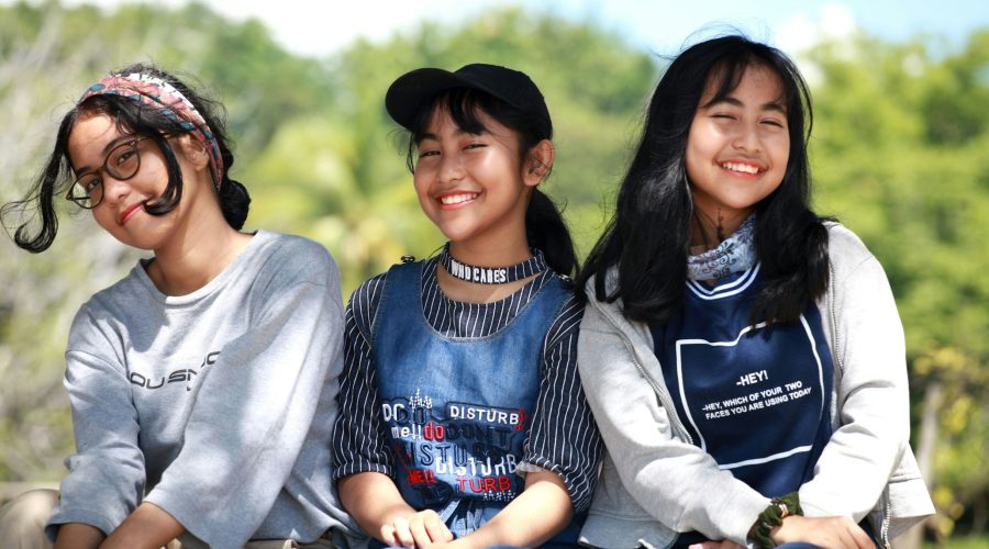three women sitting near trees