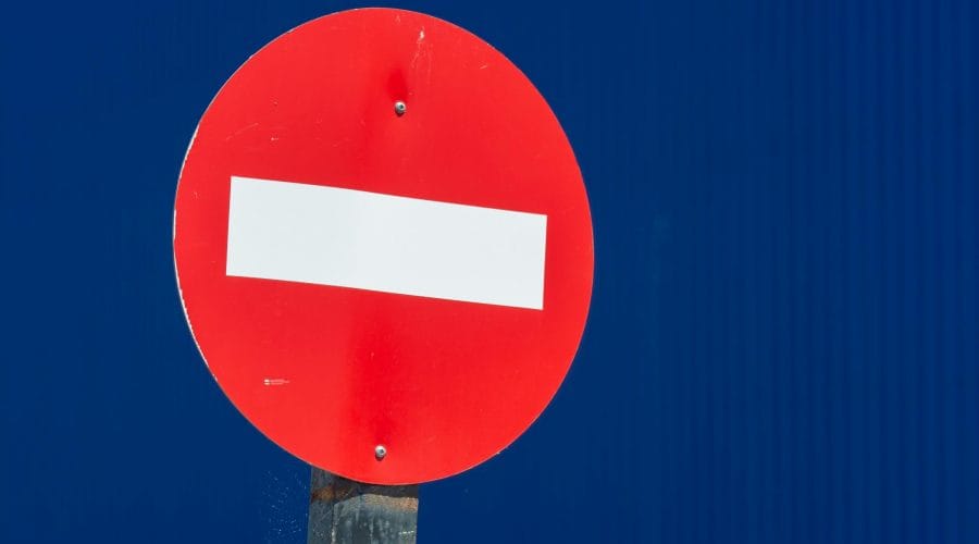 Vivid red do not enter sign with white bar on blue backdrop, ideal for travel warnings.