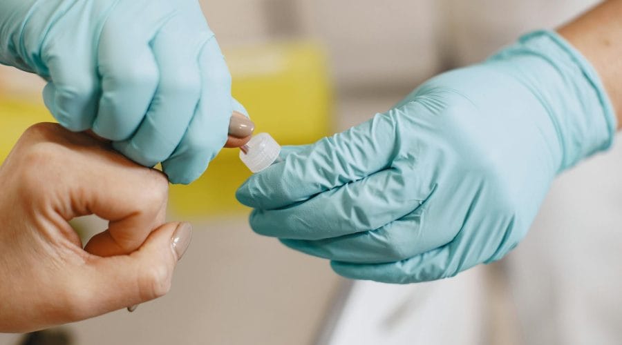 Close-up of a healthcare worker performing a blood test using sterile gloves.
