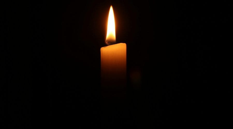 A single burning candle in the dark, casting a warm and serene glow.