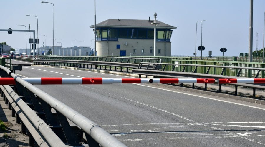 A road with a barrier and a control tower building.